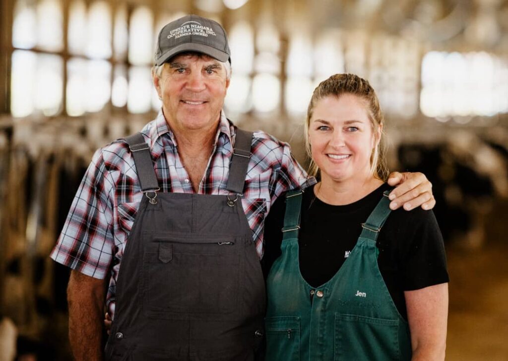 Father and daughter standing together in a dairy cow barn